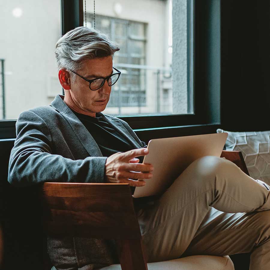 Mature businessman sitting in office lobby with a laptop. Male executive working in office lounge.